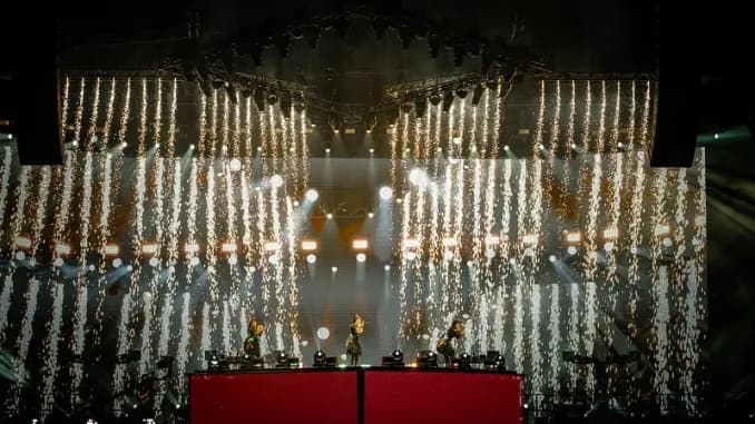 BABYMETAL en uno de los grandes escenarios del mundo, foto épica del trío con producción de luces y pirotecnia representando el alcance global de la banda